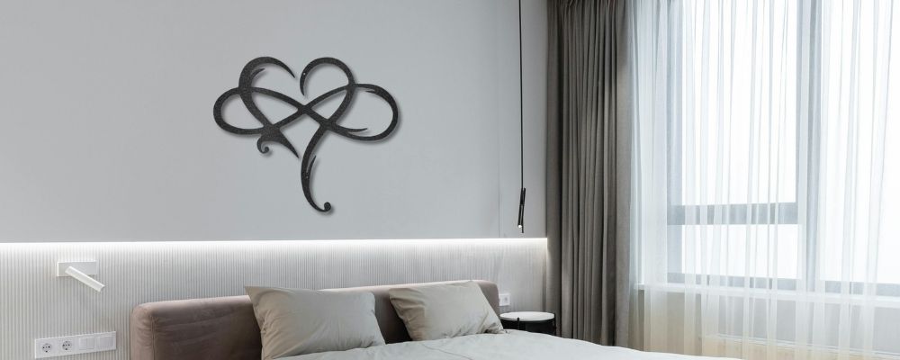 Romantic custom metal wall decor for couples, hung on a bedroom wall over the headboard of a bed. Infinity sign shown horizontally and a beautifally sculped heart shown vertically.
