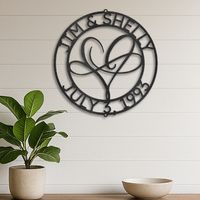 Custom steel sign with the names of a couple across the upper portion of the rim of a circle with a special date shown across the bottom rim of the circle design.  In the middle is a modern shape of a heart with a horizontal image of an infinity sign, designed for couples or as a romantic gift.