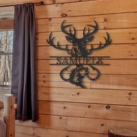 Custom steel signs for hunters, showing a piece of metal wall art hanging on a cabin wall with the silhouette of a buck and fish as well as a name across the middle.